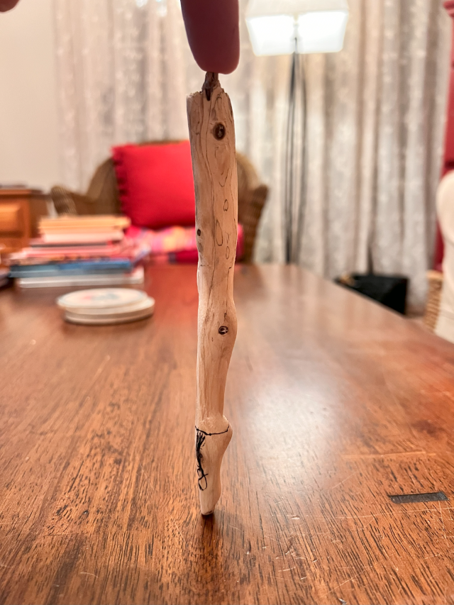 A miniature wooden ballerina leg in repose, meticulously carved to resemble the artist's own leg and thigh.