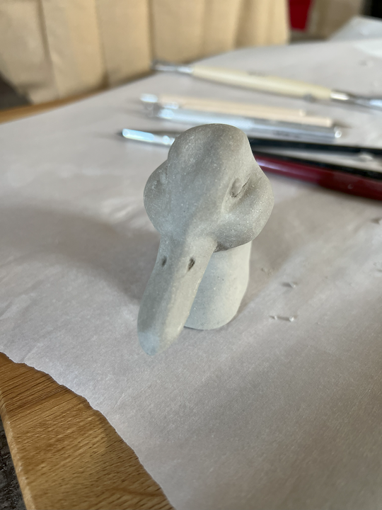 Front profile view of a clay sculpture that portrays the head of a mallard duck