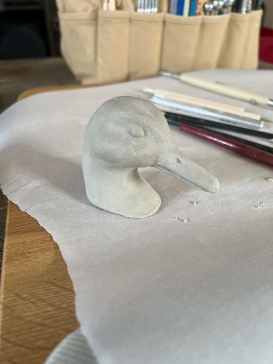 A clay sculpture that portrays the head of a mallard duck
