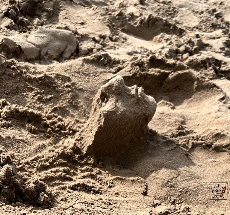 Sand sculpture of the lower half of a human head with the top portion absent.