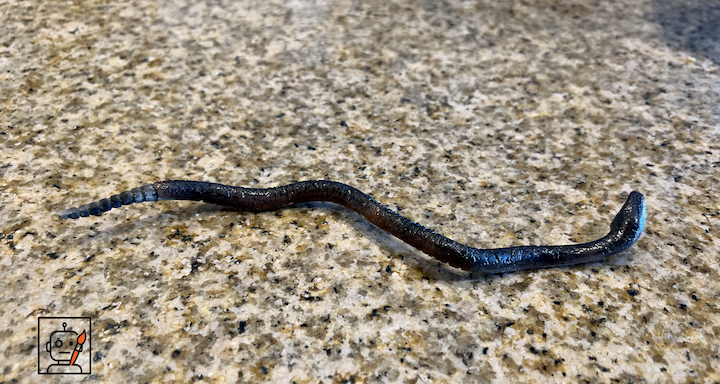 Hand-carved wooden rattlesnake sculpture with segmented tail, placed on a granite surface.